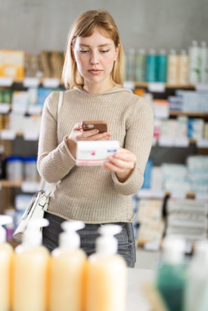 Young woman customer scanning QR-code on paracetamol boxの写真素材