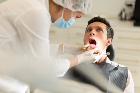 Young female dentist examining male patientの写真素材