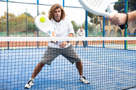 Caucasian man playing paddle tennis on padel courtの写真素材
