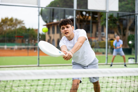 Young focused guy playing paddle tennis outdoorsの写真素材
