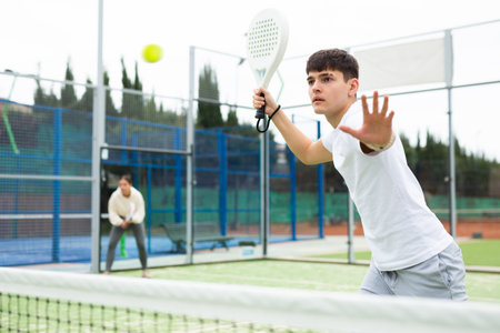 Man in sportswear playing padel tennis match during training on courtの写真素材
