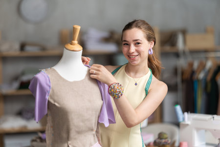 Woman seamstress adjusts clothes on mannequinの写真素材