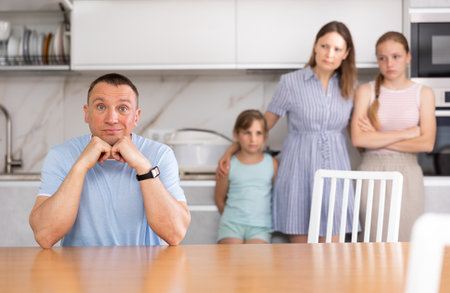 Wife and children stand behind dad and are afraid to ask about current problemの写真素材
