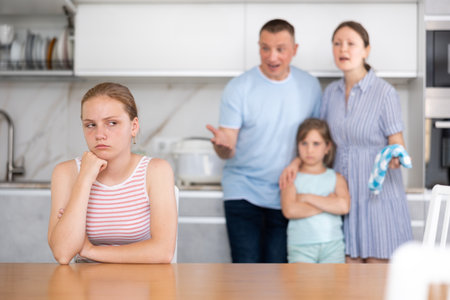 Offended teenage girl listening to disapproving words of parentsの写真素材