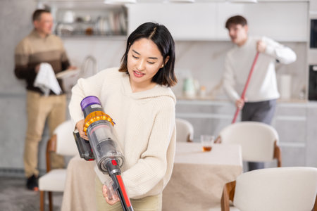 Young woman vacuuming kitchen floorの写真素材