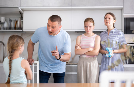 Girl with hair in braids stands in front of parents and listens to instructions about bad behaviorの写真素材