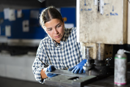 Young woman cutting holes in metal on machineの写真素材