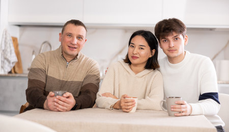 Adult man and couple sitting at table in kitchenの写真素材