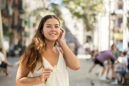 Portrait of a young girl in a light summer dress on city street during the dayの写真素材