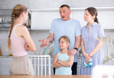 Teenage girl listening to disapproving words of father and motherの写真素材