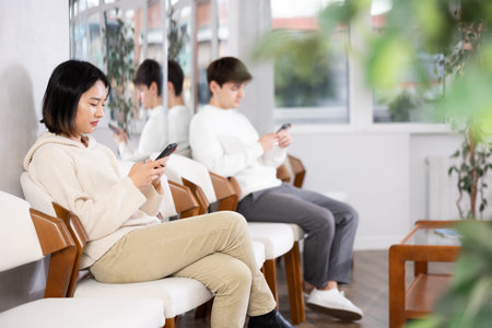 Young woman sitting in line with phoneの写真素材
