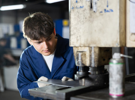 Young worker working on a hydraulic press - punching holes in metal plateの写真素材