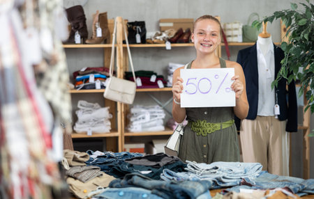 Teen girl holding discount sign in clothing store