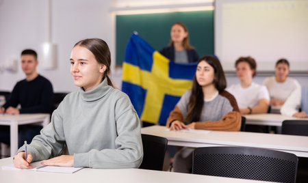 Teacher stands behind students with flag of Swedenの写真素材