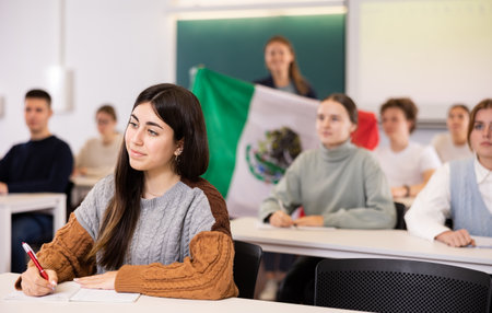 Female teacher tells her classmates about the country of Mexico, holding a flag in handsの写真素材