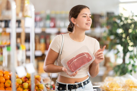 Young woman choosing entrecote in grocery storeの写真素材