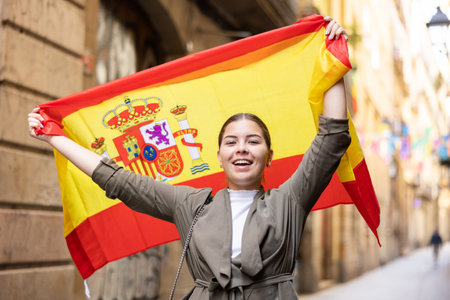 Happy female tourist walking old streets with flag of spainの写真素材