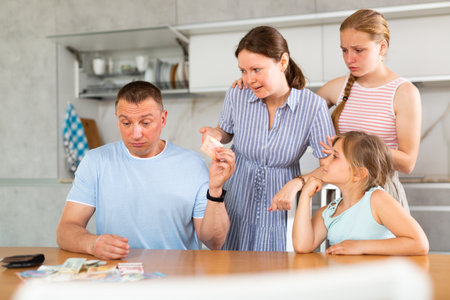 Spouses discuss unpleasant financial issue in kitchen, irritated wife takes money from husbandの写真素材