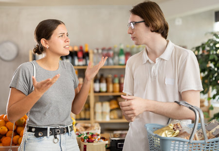 Young man and woman quarreling in grocery storeの写真素材