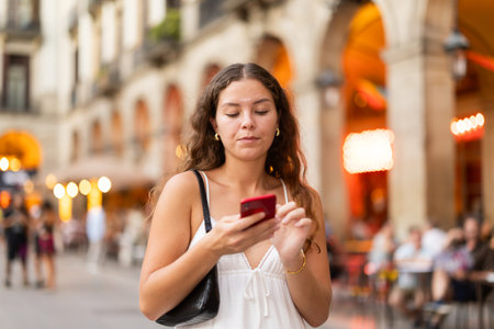 Young woman with phone walking around Barcelonaの写真素材
