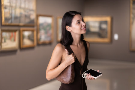 Brunette with phone in hand came to the art galleryの写真素材