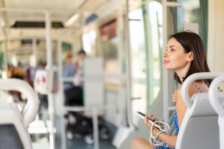 Adult woman with phone sits in subway carの写真素材