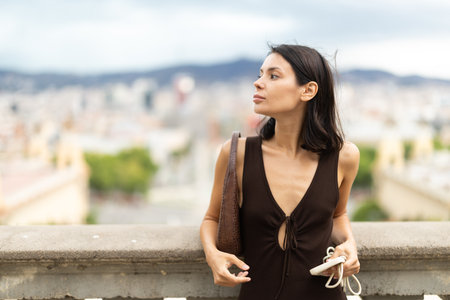 Young woman standing on street with mobile in her handsの写真素材
