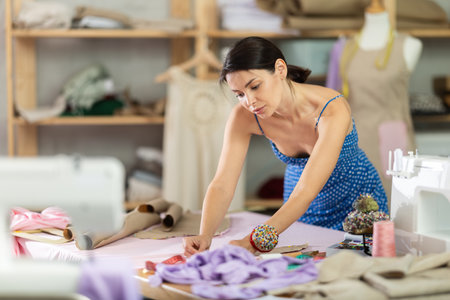 Young female seamstress attaching template to fabricの写真素材