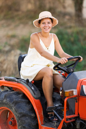 Young woman driving tractor in countrysideの写真素材