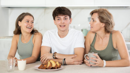Girl and guy have nice conversation with woman, mom, during Sunday tea partyの写真素材