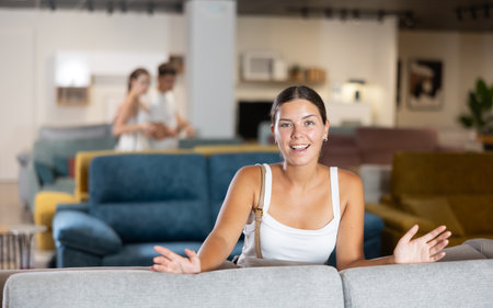 Woman choosing new sofa in furniture salon, testing softness of cushions and examining quality of upholsteryの写真素材