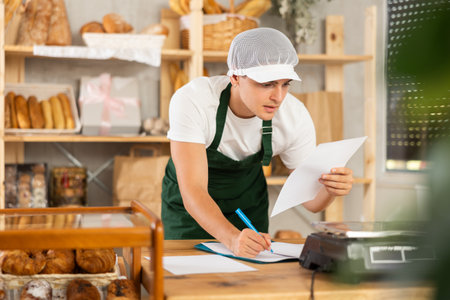 Confident young bakery manager reviewing paperworkの写真素材
