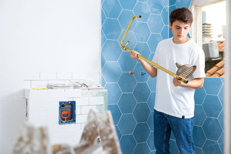 Young man assembles and installs a new shower in bathroom