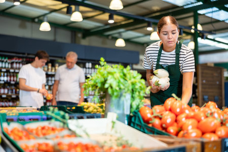 European female seller in apron takes turnip from windowの写真素材