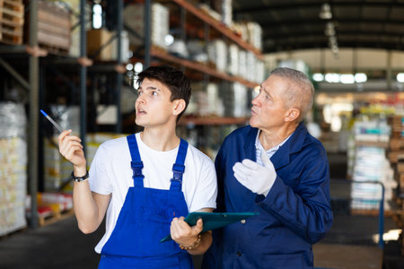 Elderly man and young guy checking documents in warehouse