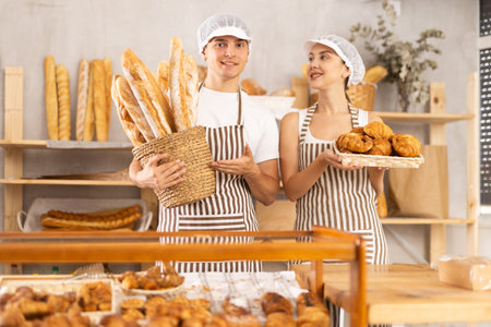 European young man and woman sellers stands in trading hall of bakeryの写真素材