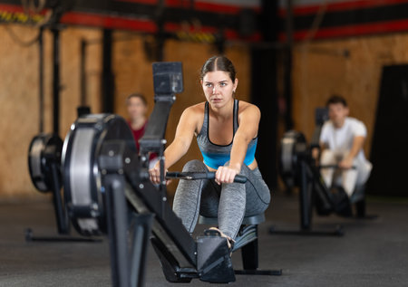 Focused girl works out with rowing machine during class at fitness clubの写真素材
