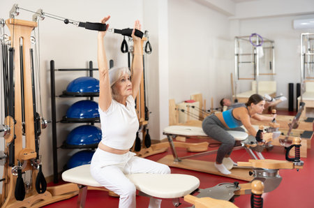 Elderly woman training her arms using straps