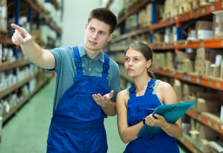 Girl check papers invoices with guy and revise availability of goods in paint and varnish stockの写真素材