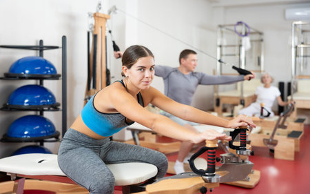 Young girl during Pilates training performs exercises and tasks on heron pulley towerの写真素材
