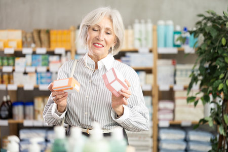 Elderly woman looking for medicine in pharmacyの写真素材