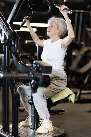 Older woman using lat pulldown machine during workout at gym