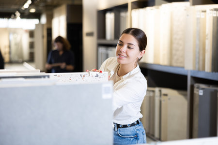 Confident female customer picking out wall tile materials for bathroom in hardware storeの写真素材