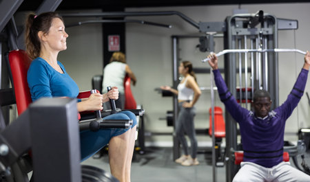 Caucasian woman doing leg raises on captains chair in gym