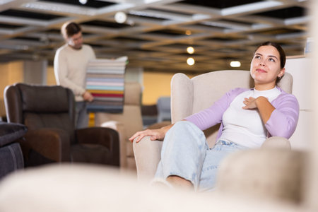 Woman trying out armchair in furniture showroom