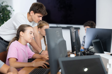 Computer science teacher helps young schoolgirl solve problem on computer