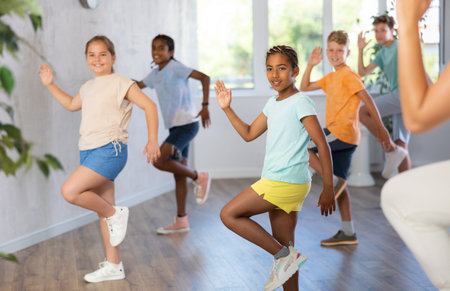 Happy boys and girls enjoying active dance in modern studio