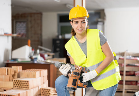 Portrait of positive woman builder standing in construction site