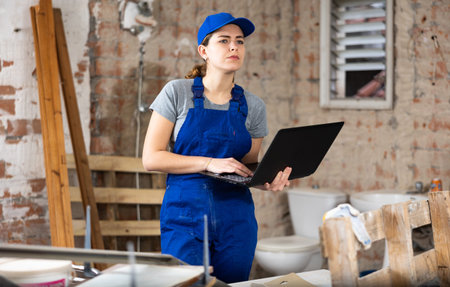 Woman construction worker using laptop in apartment