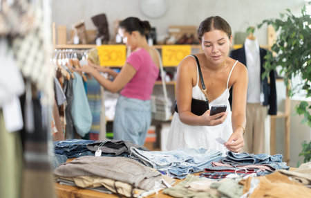 Glad young woman scanning QR-code on jeans in clothing store